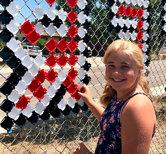 smiling girl decorating a fence